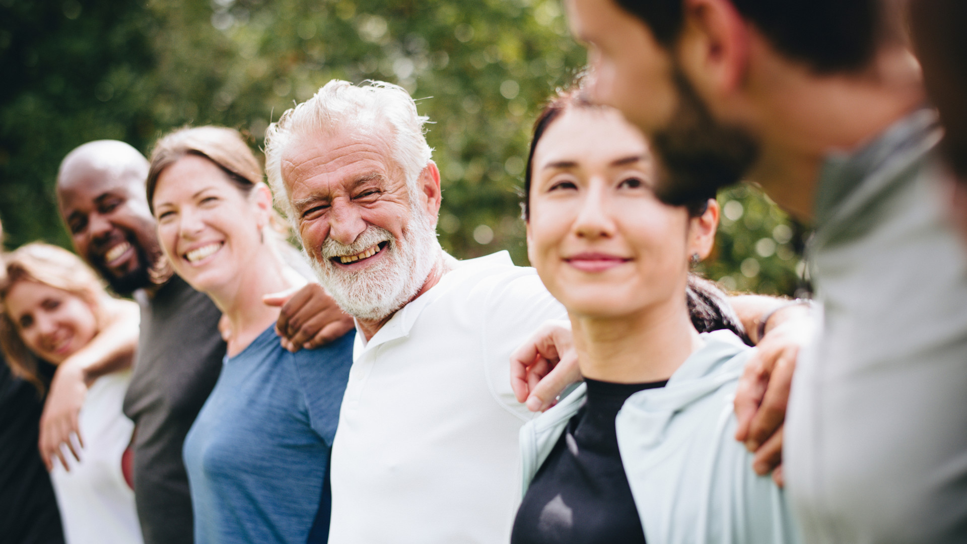 Fröhliche diverse Menschen umarmen sich und sind glücklich.