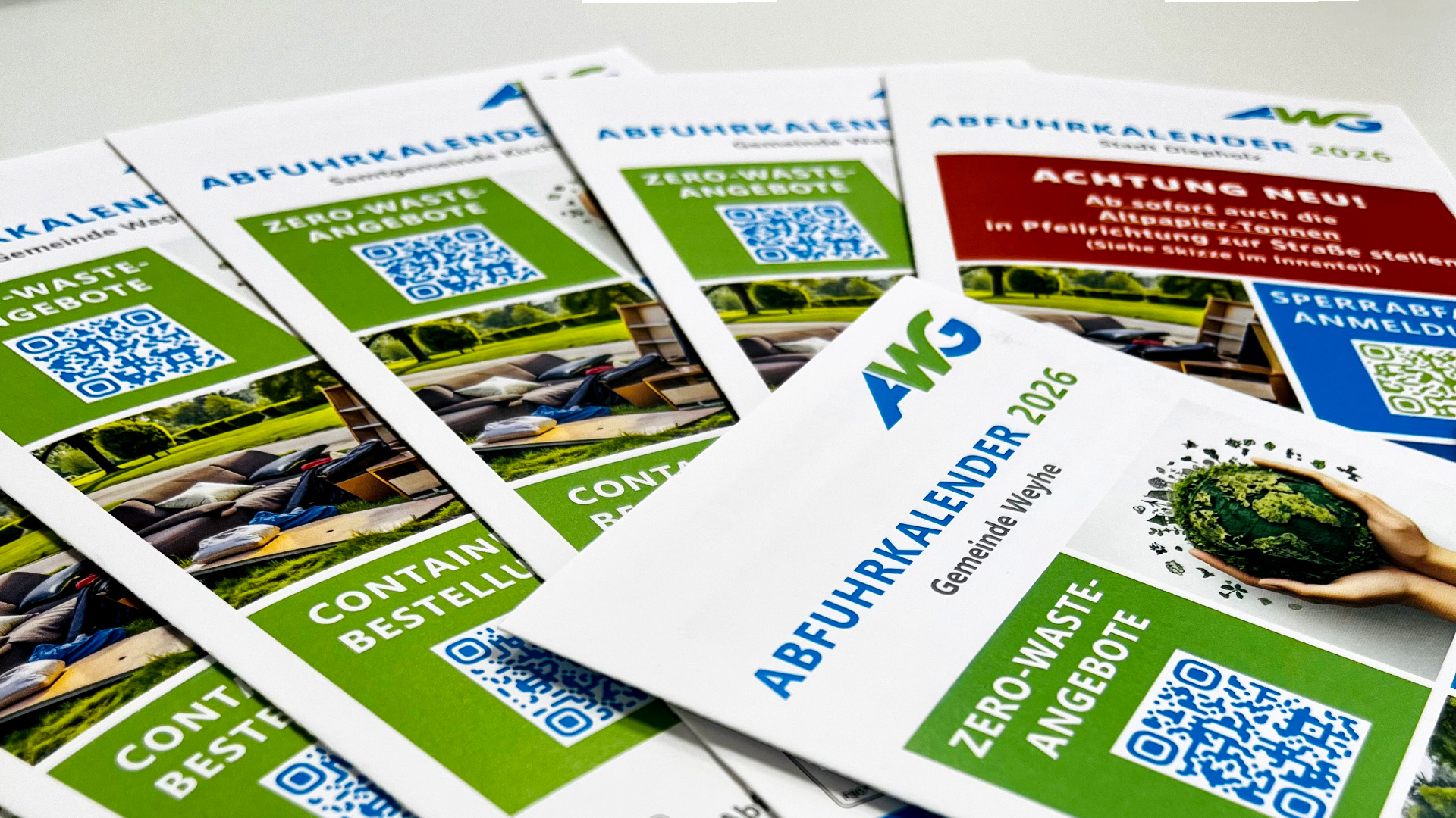 Eine Auswahl an Abfuhrkalendern liegen auf einem Tisch.