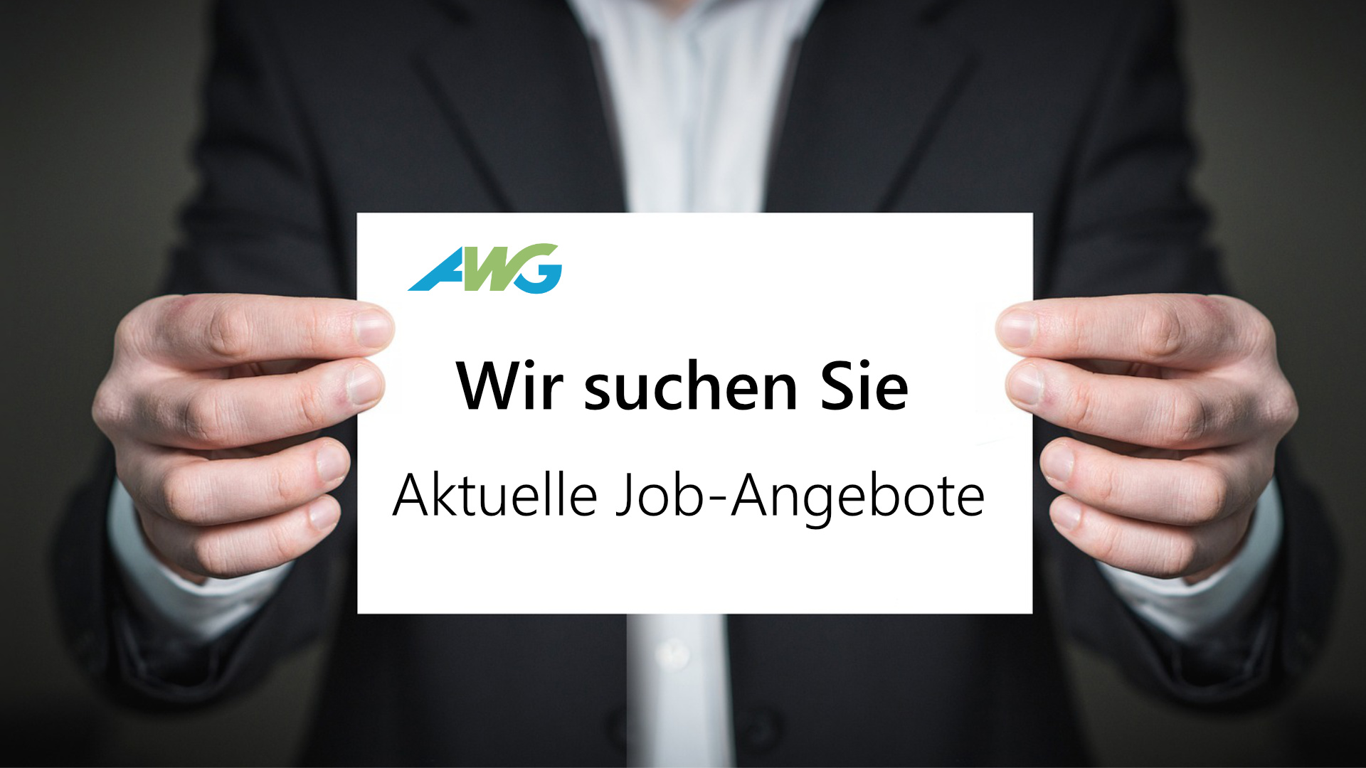 Eine Person hält eine Karte in die Kamera mit dem AWG-Logo und dem Text "Wir suchen Sie".